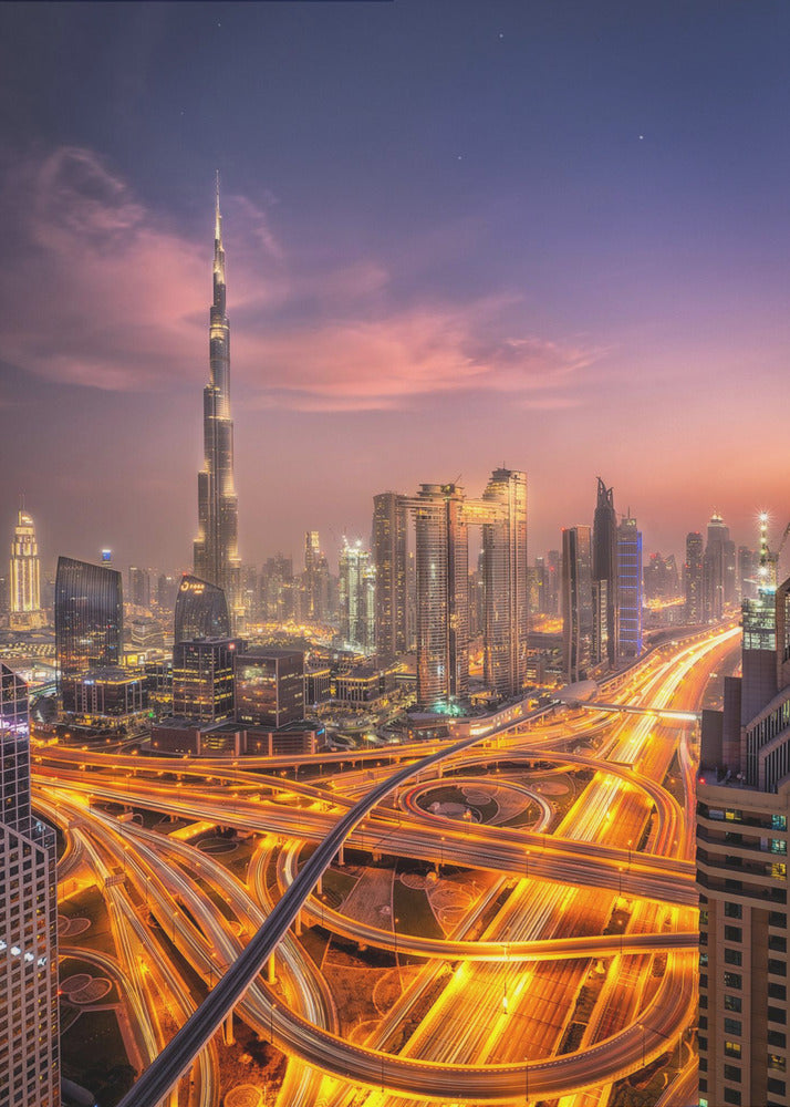A stunning aerial photograph of the Dubai skyline at dusk, featuring the illuminated Burj Khalifa against a purple and pink sunset sky. In the foreground, complex highway interchanges are aglow with the golden-orange light trails of moving traffic, creating a sense of vibrant energy. Poster