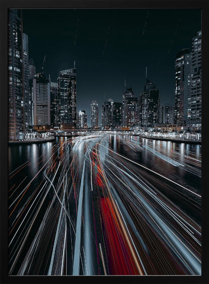 A dynamic long-exposure photograph of a bustling city marina at night. In the foreground, vibrant streaks of red and white light from moving boats cut across the dark water. In the background, a modern skyline of illuminated skyscrapers stands against a dark night sky, creating a futuristic and energetic scene. Poster