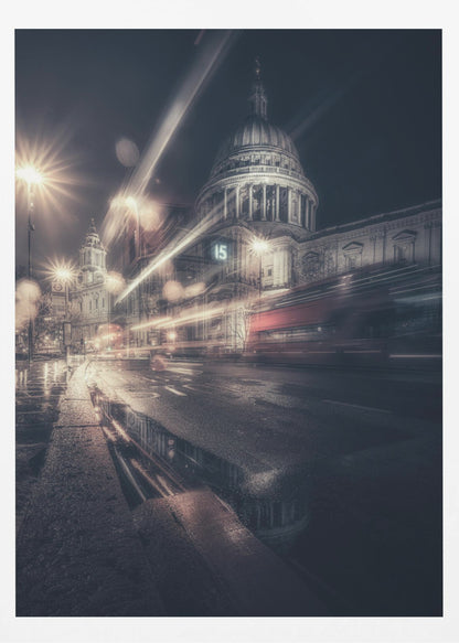 A dynamic long-exposure photograph of a wet London street at night, with the iconic dome of St. Paul's Cathedral illuminated in the background. Streaks of light from passing traffic, including a red bus, blur across the scene, while the glistening pavement reflects the cathedral and bright streetlights. Decor