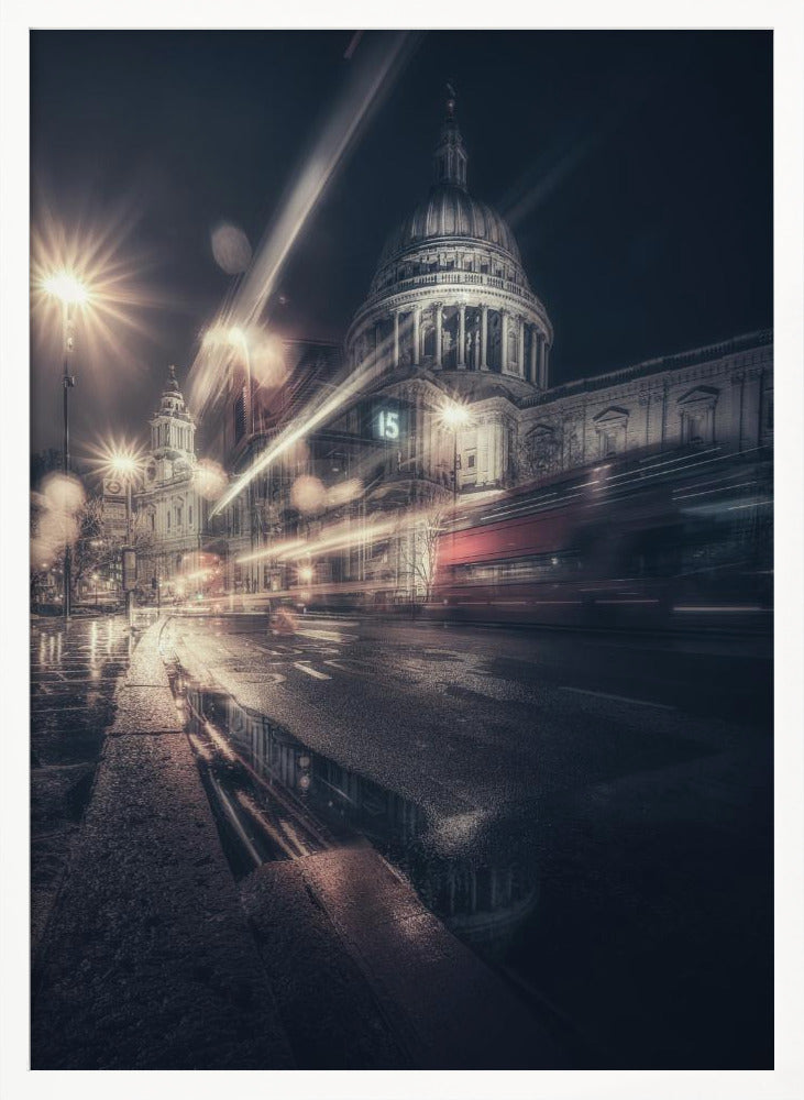 A dynamic long-exposure photograph of a wet London street at night, with the iconic dome of St. Paul's Cathedral illuminated in the background. Streaks of light from passing traffic, including a red bus, blur across the scene, while the glistening pavement reflects the cathedral and bright streetlights. Decor