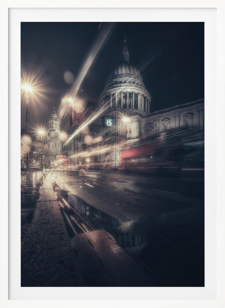 A dynamic long-exposure photograph of a wet London street at night, with the iconic dome of St. Paul's Cathedral illuminated in the background. Streaks of light from passing traffic, including a red bus, blur across the scene, while the glistening pavement reflects the cathedral and bright streetlights. Decor