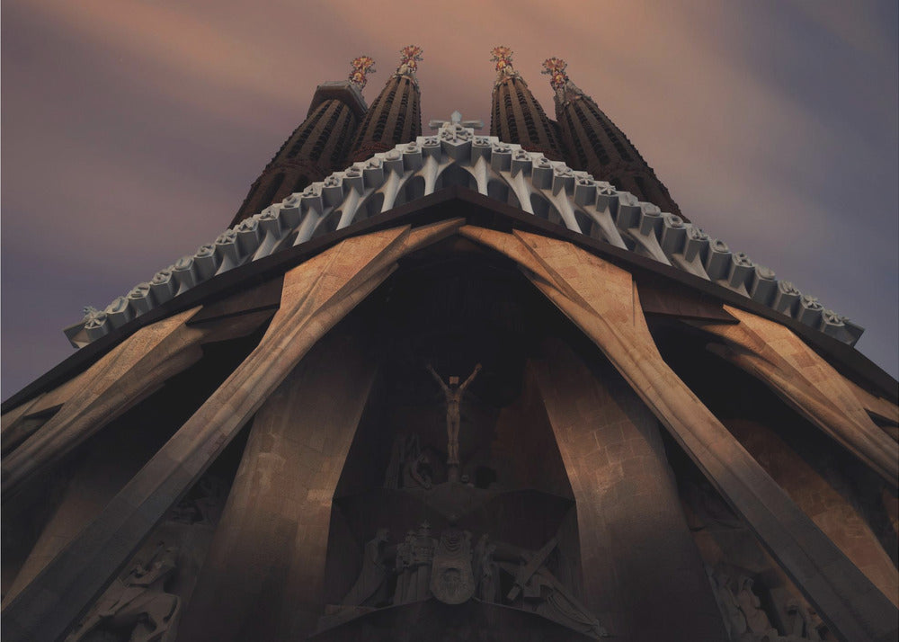 A dramatic, low-angle shot of the Sagrada Familia cathedral, focusing on the intricate details of the Passion Facade against a dusky purple and orange sky. The spires tower above, while deep shadows highlight the unique, angled columns and the central sculpture of the crucifixion. Poster
