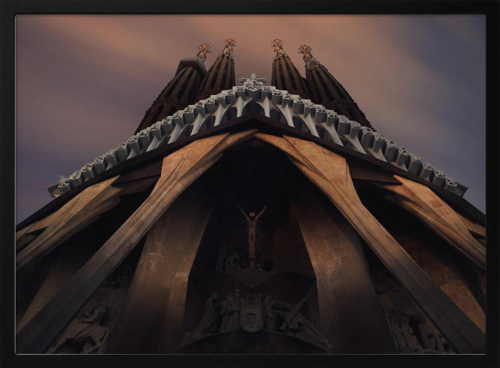 A dramatic, low-angle shot of the Sagrada Familia cathedral, focusing on the intricate details of the Passion Facade against a dusky purple and orange sky. The spires tower above, while deep shadows highlight the unique, angled columns and the central sculpture of the crucifixion. Poster