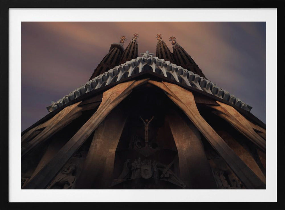 A dramatic, low-angle shot of the Sagrada Familia cathedral, focusing on the intricate details of the Passion Facade against a dusky purple and orange sky. The spires tower above, while deep shadows highlight the unique, angled columns and the central sculpture of the crucifixion. Poster