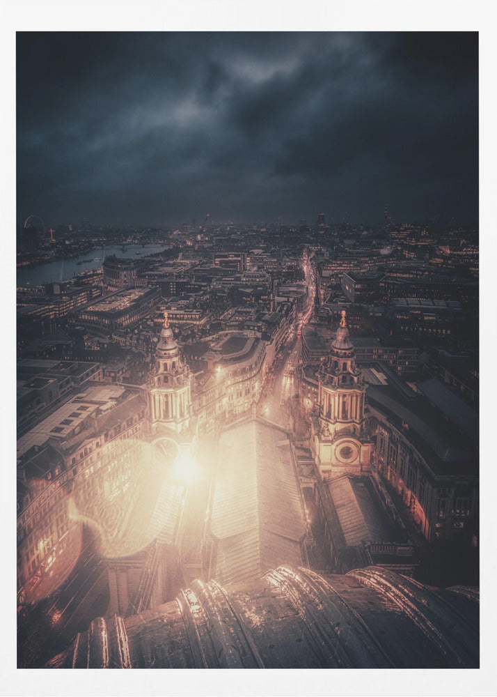 A dramatic, high-angle nighttime photograph of a sprawling city, likely London, viewed from the top of a cathedral. The foreground shows the curved dome, while below, two towers and the long roof of the church are brightly illuminated. The city stretches into the distance with countless golden lights under a dark, stormy, and cloud-filled sky. Poster