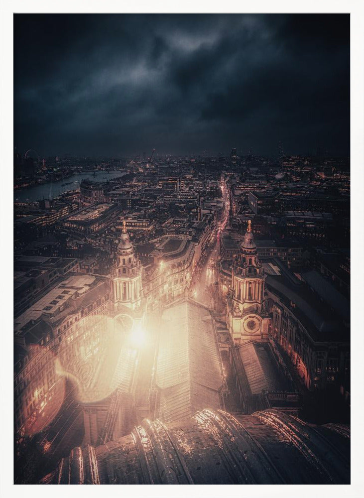 A dramatic, high-angle nighttime photograph of a sprawling city, likely London, viewed from the top of a cathedral. The foreground shows the curved dome, while below, two towers and the long roof of the church are brightly illuminated. The city stretches into the distance with countless golden lights under a dark, stormy, and cloud-filled sky. Poster