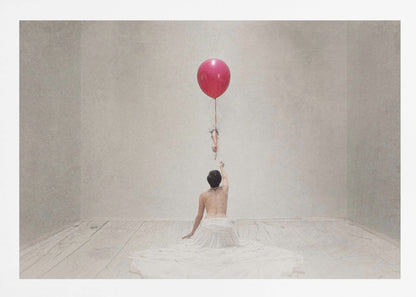 A surreal fine art photograph of a person with a bare back and a long white skirt, sitting on the floor of a minimalist grey room. They are reaching up towards a small figure hanging from the string of a large, bright red balloon that floats towards the ceiling. The image is enclosed in a silver frame. Artwork