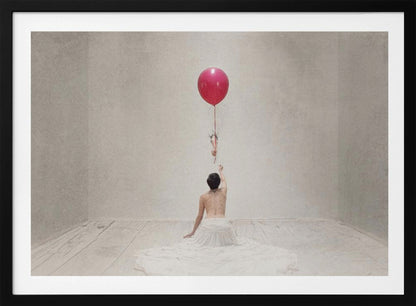 A surreal fine art photograph of a person with a bare back and a long white skirt, sitting on the floor of a minimalist grey room. They are reaching up towards a small figure hanging from the string of a large, bright red balloon that floats towards the ceiling. The image is enclosed in a silver frame. Artwork