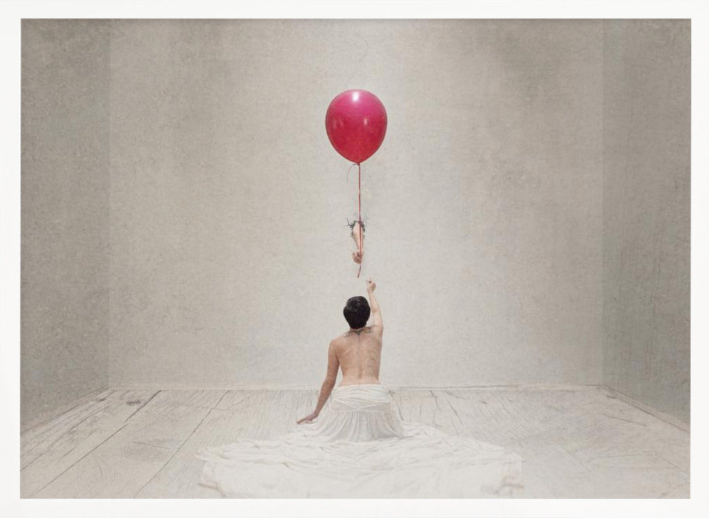 A surreal fine art photograph of a person with a bare back and a long white skirt, sitting on the floor of a minimalist grey room. They are reaching up towards a small figure hanging from the string of a large, bright red balloon that floats towards the ceiling. The image is enclosed in a silver frame. Artwork