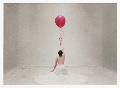 A surreal fine art photograph of a person with a bare back and a long white skirt, sitting on the floor of a minimalist grey room. They are reaching up towards a small figure hanging from the string of a large, bright red balloon that floats towards the ceiling. The image is enclosed in a silver frame. Artwork