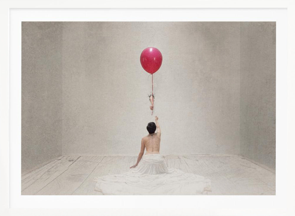A surreal fine art photograph of a person with a bare back and a long white skirt, sitting on the floor of a minimalist grey room. They are reaching up towards a small figure hanging from the string of a large, bright red balloon that floats towards the ceiling. The image is enclosed in a silver frame. Artwork