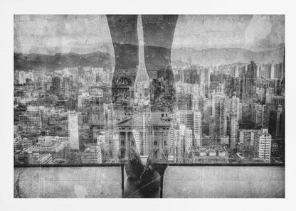 A framed, black and white artistic photograph featuring a double exposure. A vast, dense cityscape with distant mountains is visible through the translucent silhouette of a person's legs standing on a balcony edge. Poster