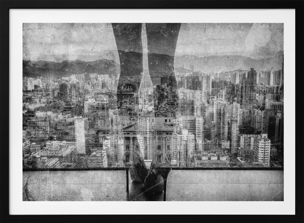 A framed, black and white artistic photograph featuring a double exposure. A vast, dense cityscape with distant mountains is visible through the translucent silhouette of a person's legs standing on a balcony edge. Poster
