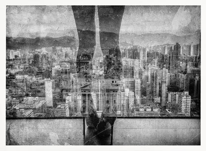 A framed, black and white artistic photograph featuring a double exposure. A vast, dense cityscape with distant mountains is visible through the translucent silhouette of a person's legs standing on a balcony edge. Poster