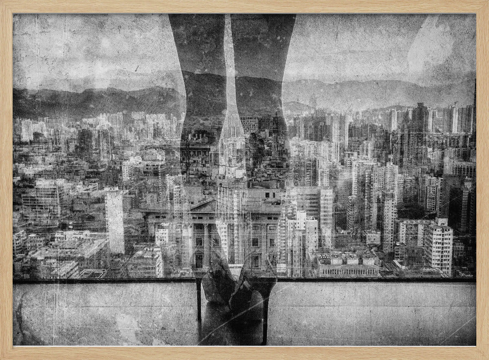 A framed, black and white artistic photograph featuring a double exposure. A vast, dense cityscape with distant mountains is visible through the translucent silhouette of a person's legs standing on a balcony edge. Poster