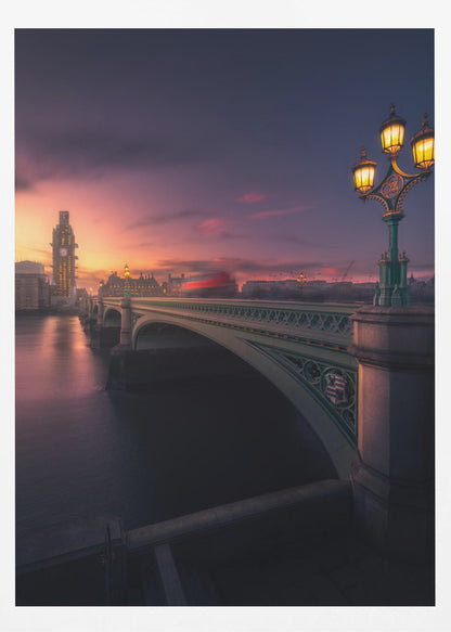 A breathtaking twilight view of Westminster Bridge in London, with the iconic Big Ben illuminated in the background against a purple and orange sunset sky. A vintage street lamp glows warmly in the foreground, and the motion blur of a red bus crosses the bridge over the calm River Thames. Print