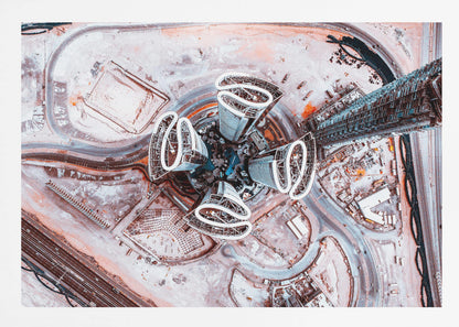 A dizzying top-down aerial photograph of five futuristic, petal-shaped skyscrapers surrounding a central turquoise pool. The surrounding urban landscape is a mix of dusty pink construction sites and curving roads, creating a surreal and abstract cityscape. Wall Art