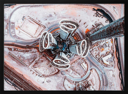 A dizzying top-down aerial photograph of five futuristic, petal-shaped skyscrapers surrounding a central turquoise pool. The surrounding urban landscape is a mix of dusty pink construction sites and curving roads, creating a surreal and abstract cityscape. Wall Art