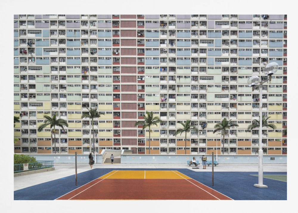 A wide, symmetrical photograph of the colorful Choi Hung Estate apartment building in Hong Kong, featuring a facade with a repeating pattern of pastel blue, green, yellow, and orange blocks. In front of the building is a vibrant basketball court painted in bold sections of blue, red, and yellow, with several palm trees lining the courtyard. Print