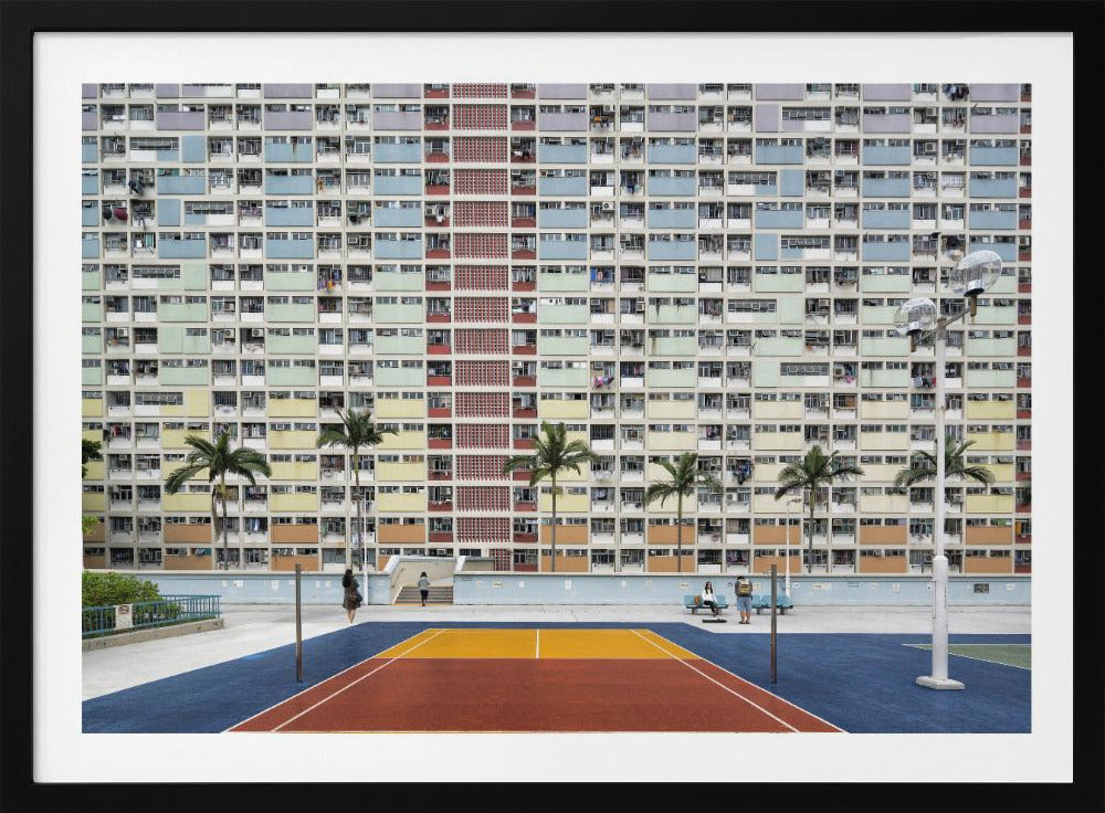 A wide, symmetrical photograph of the colorful Choi Hung Estate apartment building in Hong Kong, featuring a facade with a repeating pattern of pastel blue, green, yellow, and orange blocks. In front of the building is a vibrant basketball court painted in bold sections of blue, red, and yellow, with several palm trees lining the courtyard. Print
