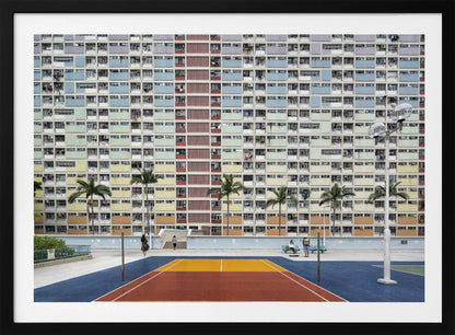 A wide, symmetrical photograph of the colorful Choi Hung Estate apartment building in Hong Kong, featuring a facade with a repeating pattern of pastel blue, green, yellow, and orange blocks. In front of the building is a vibrant basketball court painted in bold sections of blue, red, and yellow, with several palm trees lining the courtyard. Print