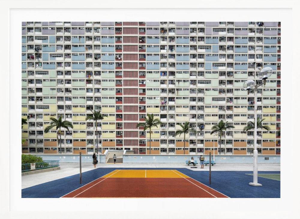 A wide, symmetrical photograph of the colorful Choi Hung Estate apartment building in Hong Kong, featuring a facade with a repeating pattern of pastel blue, green, yellow, and orange blocks. In front of the building is a vibrant basketball court painted in bold sections of blue, red, and yellow, with several palm trees lining the courtyard. Print
