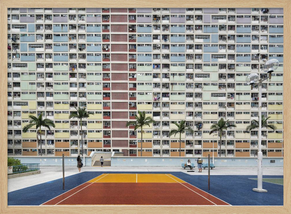 A wide, symmetrical photograph of the colorful Choi Hung Estate apartment building in Hong Kong, featuring a facade with a repeating pattern of pastel blue, green, yellow, and orange blocks. In front of the building is a vibrant basketball court painted in bold sections of blue, red, and yellow, with several palm trees lining the courtyard. Print