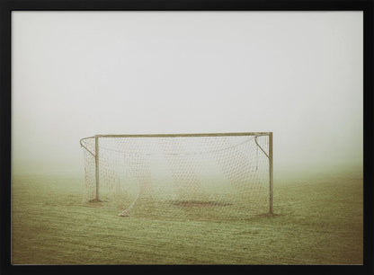 A framed photograph of an empty soccer goal with a net, standing alone on a green grass field enveloped in thick, white fog, creating a minimalist and atmospheric scene. Poster