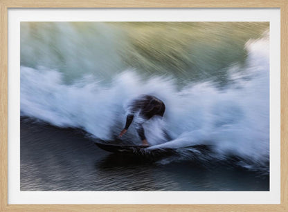 An abstract, motion-blur photograph of a surfer in a black wetsuit, crouched on their board and surrounded by a dynamic swirl of white sea spray and dark blue water, all enclosed in a silver frame. Artwork