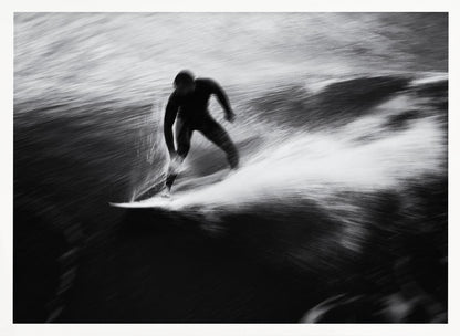 A dynamic black and white photograph of a surfer in a wetsuit carving through a wave. The image uses motion blur to emphasize the speed and energy of the water, creating a powerful and artistic effect. The artwork is presented in a simple silver frame. Print