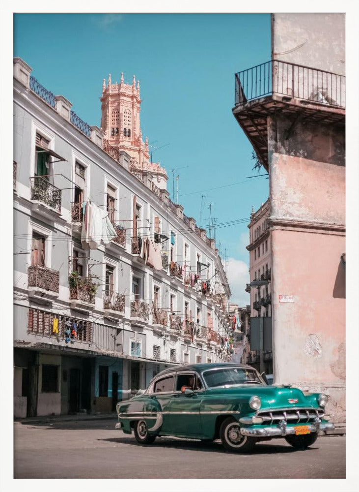 A vintage teal-green classic car sits on a sunny street in a historic city, possibly Havana, Cuba. Weathered apartment buildings with intricate balconies and hanging laundry line the street, with a peach-colored church tower visible in the background against a clear turquoise sky. Poster