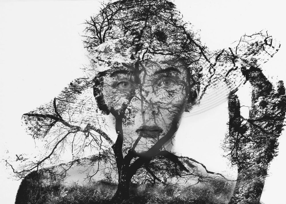 A surreal black and white double exposure artwork in a silver frame. The image combines a close-up portrait of a person's face with the intricate silhouette of bare, branching trees against a white background, creating a complex and thought-provoking visual. Poster