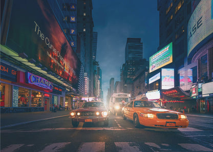A cinematic night-time view of a busy city street, likely Times Square, with a vintage red muscle car and a yellow taxi cab side-by-side in the foreground, surrounded by towering skyscrapers and glowing neon billboards. Artwork