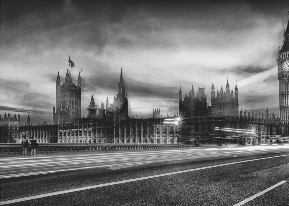 A framed, black and white long-exposure photograph of the Houses of Parliament and Big Ben in London. The view is from a bridge, with streaks of white light from traffic blurring across the road in the foreground under a dramatic, cloudy sky. Wall Art
