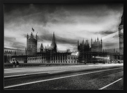 A framed, black and white long-exposure photograph of the Houses of Parliament and Big Ben in London. The view is from a bridge, with streaks of white light from traffic blurring across the road in the foreground under a dramatic, cloudy sky. Wall Art