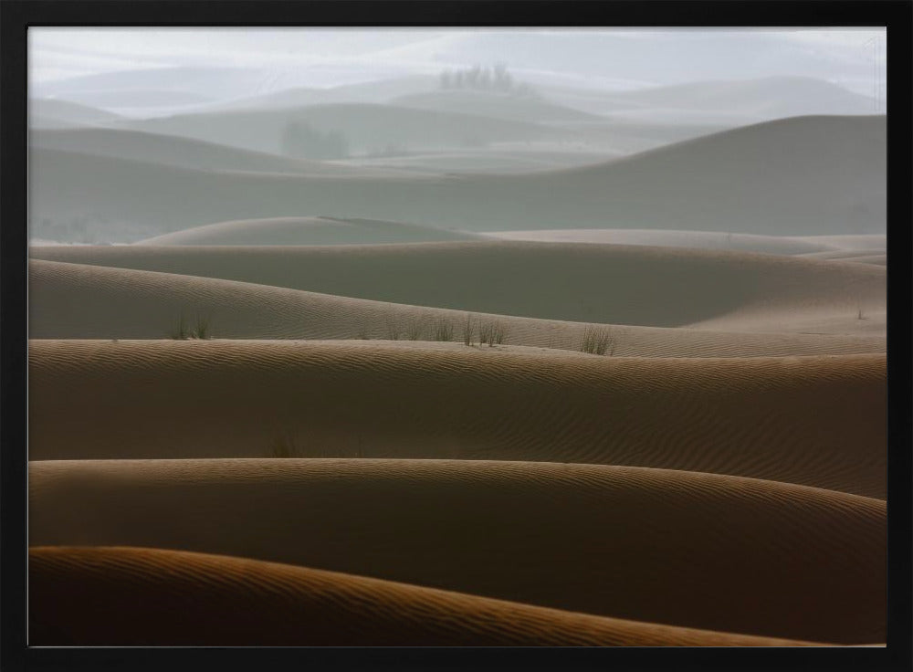 A framed photograph of a serene desert landscape, with layers of rolling sand dunes creating a sense of depth. Dark brown dunes in the foreground give way to lighter, hazy dunes and hills in the misty background. Print