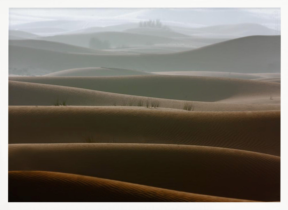 A framed photograph of a serene desert landscape, with layers of rolling sand dunes creating a sense of depth. Dark brown dunes in the foreground give way to lighter, hazy dunes and hills in the misty background. Print