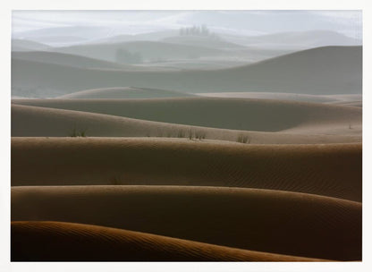 A framed photograph of a serene desert landscape, with layers of rolling sand dunes creating a sense of depth. Dark brown dunes in the foreground give way to lighter, hazy dunes and hills in the misty background. Print