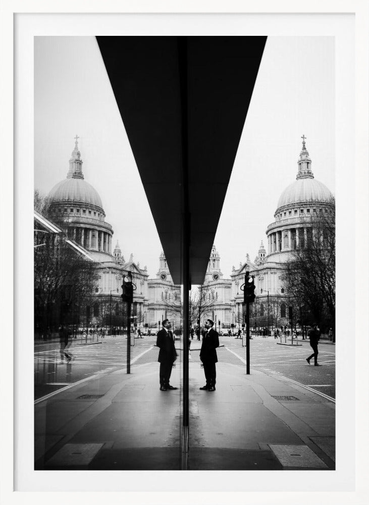 A surreal black and white photograph capturing a symmetrical reflection of a city scene, with St. Paul's Cathedral prominently featured on both sides. A dark, V-shaped reflection from a building divides the image vertically. In the foreground, the reflection of two men in dark suits standing on the sidewalk adds a human element to the grand architectural view. Decor