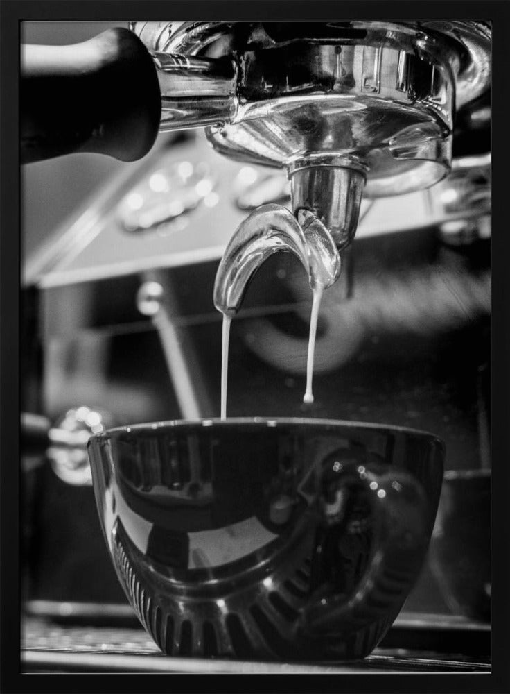 A close-up, black and white photograph of an espresso machine pouring two streams of fresh coffee from a chrome portafilter into a dark, glossy cup. Print