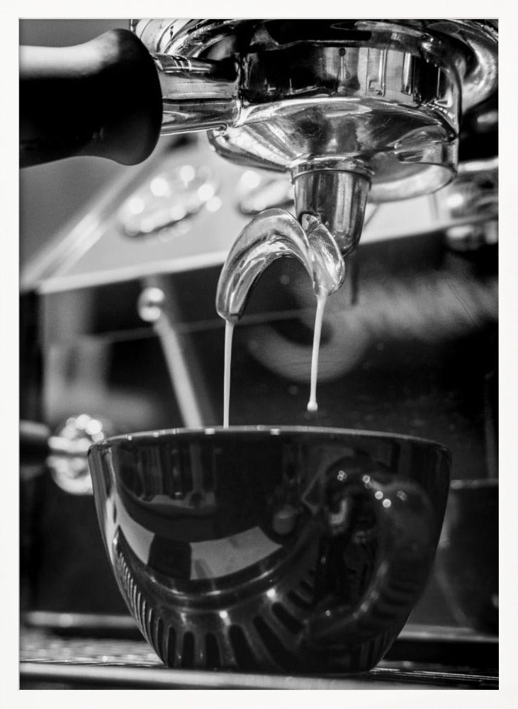 A close-up, black and white photograph of an espresso machine pouring two streams of fresh coffee from a chrome portafilter into a dark, glossy cup. Print