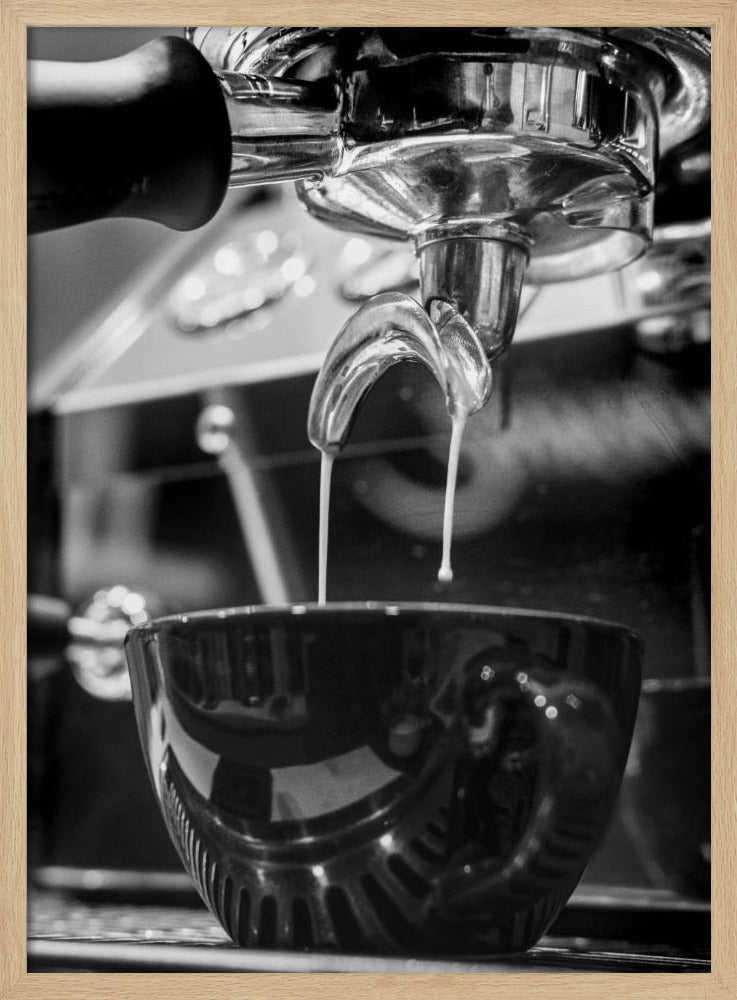 A close-up, black and white photograph of an espresso machine pouring two streams of fresh coffee from a chrome portafilter into a dark, glossy cup. Print