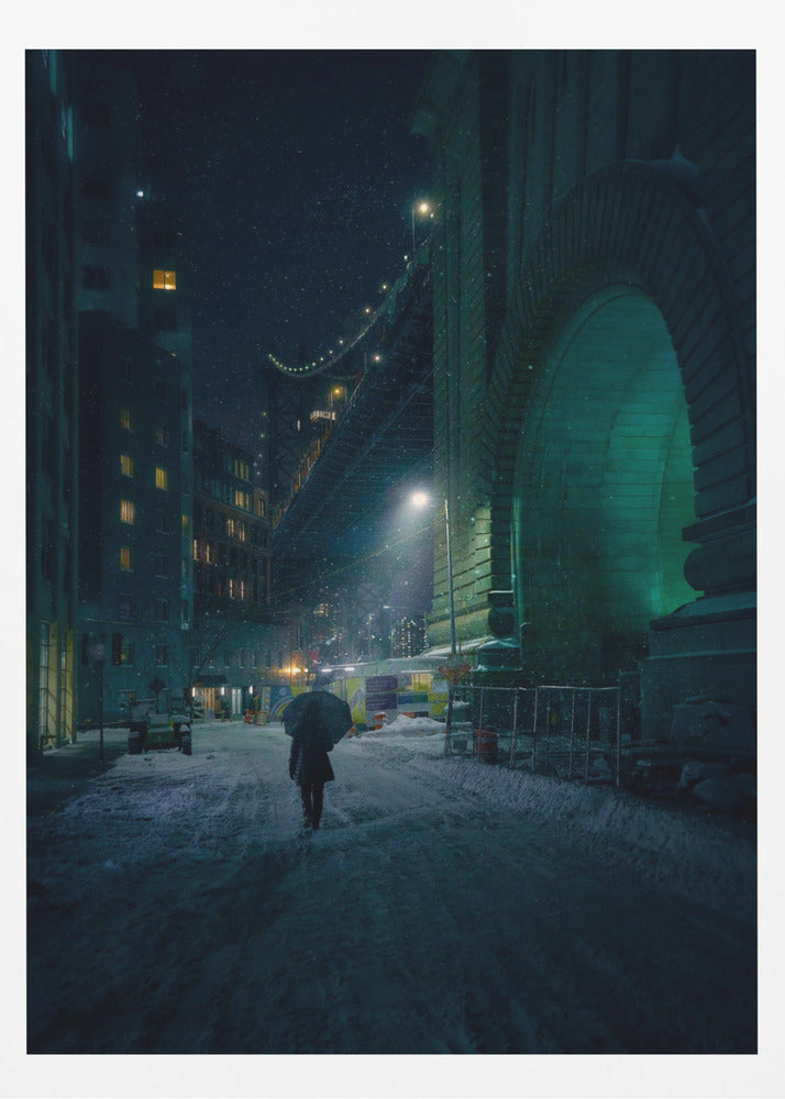 A lone person holding an umbrella walks down a snow-covered street at night, dwarfed by the massive, green-lit stone archway of the Brooklyn Bridge as snow falls around them. Print