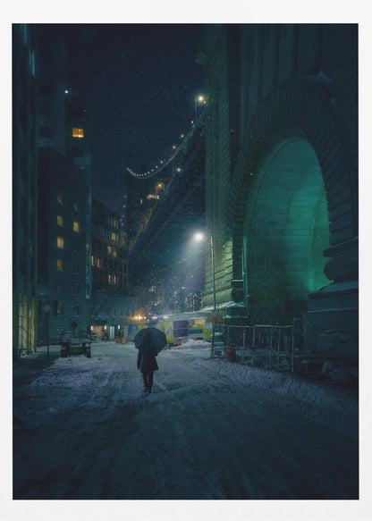 A lone person holding an umbrella walks down a snow-covered street at night, dwarfed by the massive, green-lit stone archway of the Brooklyn Bridge as snow falls around them. Print
