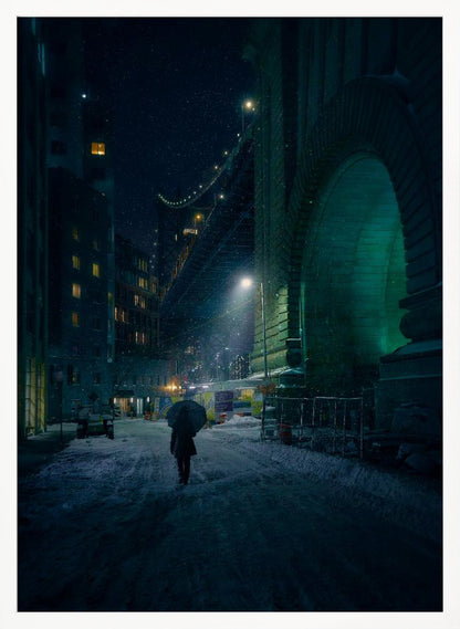 A lone person holding an umbrella walks down a snow-covered street at night, dwarfed by the massive, green-lit stone archway of the Brooklyn Bridge as snow falls around them. Print