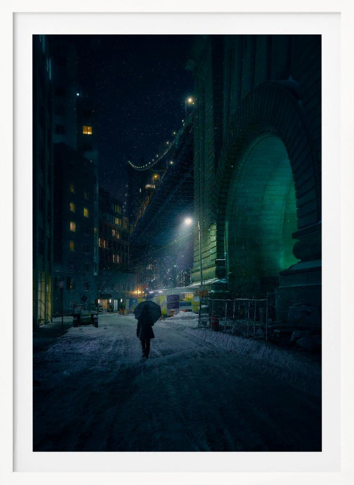A lone person holding an umbrella walks down a snow-covered street at night, dwarfed by the massive, green-lit stone archway of the Brooklyn Bridge as snow falls around them. Print
