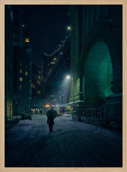 A lone person holding an umbrella walks down a snow-covered street at night, dwarfed by the massive, green-lit stone archway of the Brooklyn Bridge as snow falls around them. Print