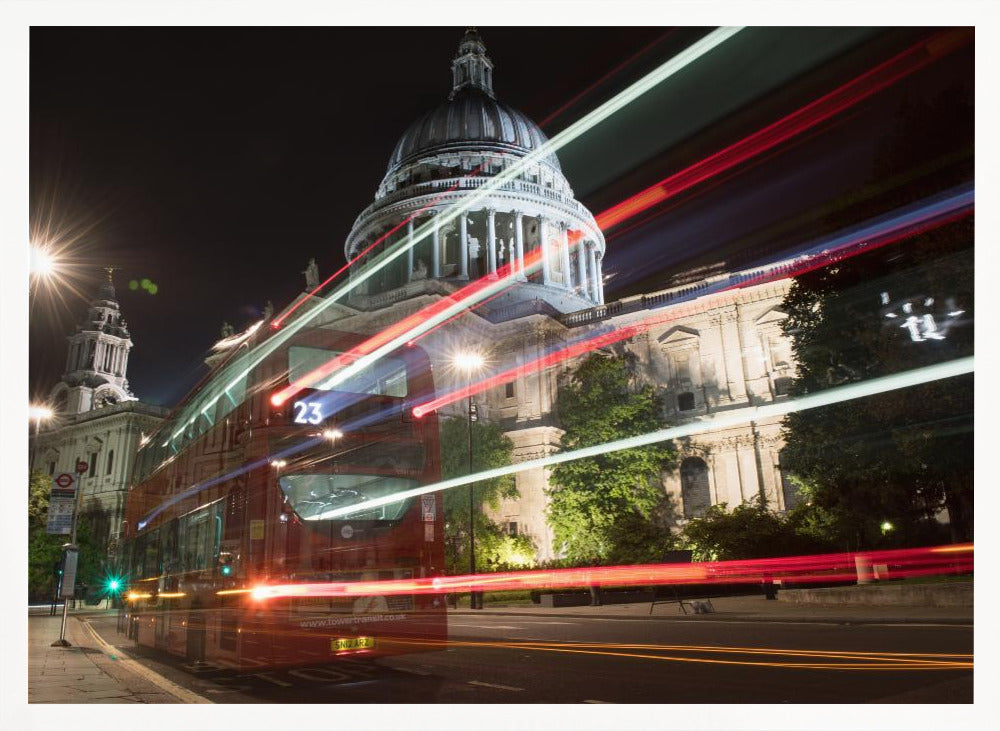 A long-exposure night photograph of a red double-decker bus in London, creating vibrant red and white light trails in front of the illuminated St. Paul's Cathedral. Decor
