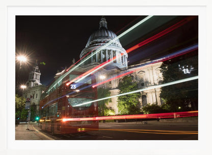A long-exposure night photograph of a red double-decker bus in London, creating vibrant red and white light trails in front of the illuminated St. Paul's Cathedral. Decor