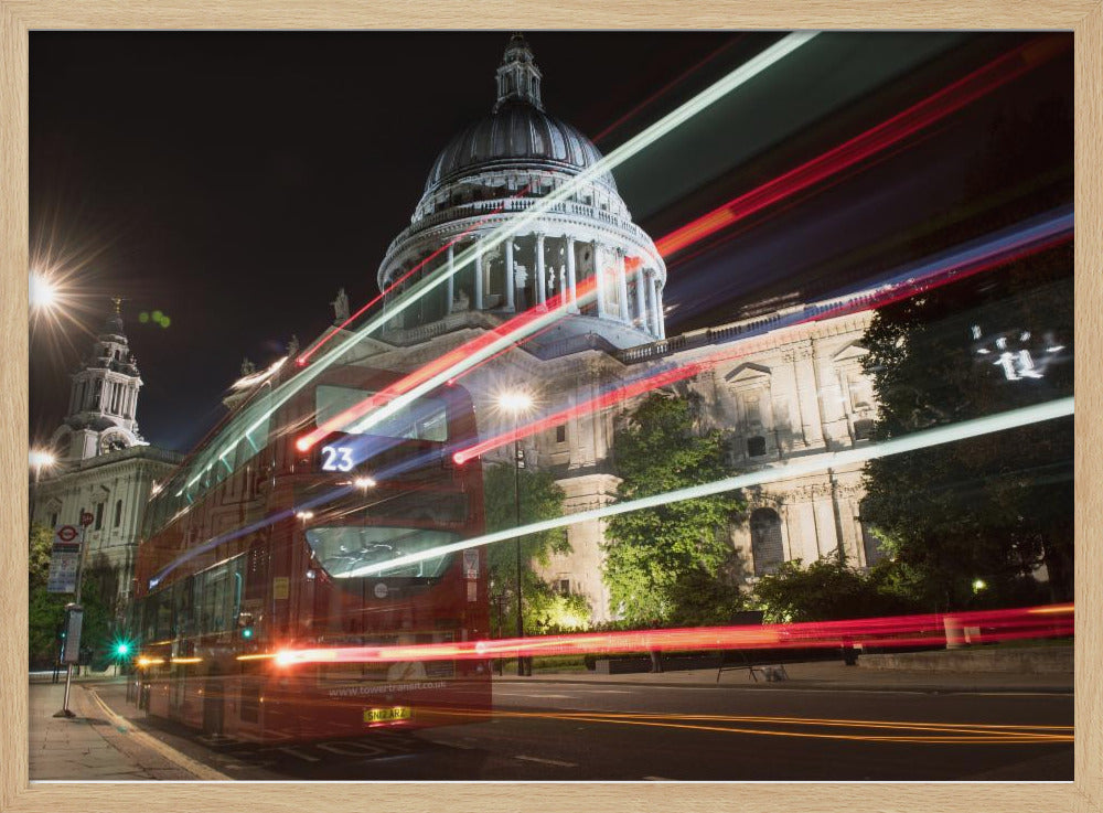 A long-exposure night photograph of a red double-decker bus in London, creating vibrant red and white light trails in front of the illuminated St. Paul's Cathedral. Decor